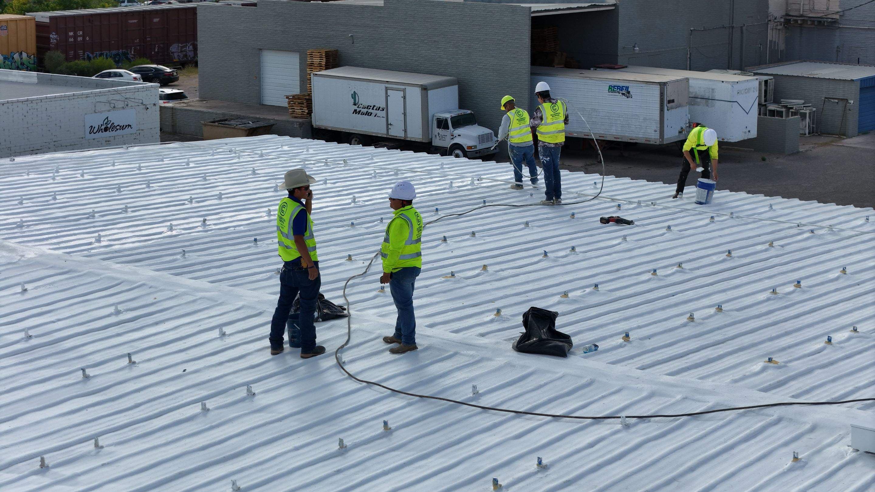 Crew applying reflective roof coating